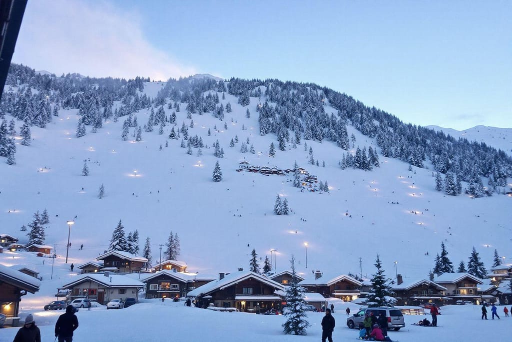 Vue d'un village de montagne enneigé, entouré de sommets enneigés.