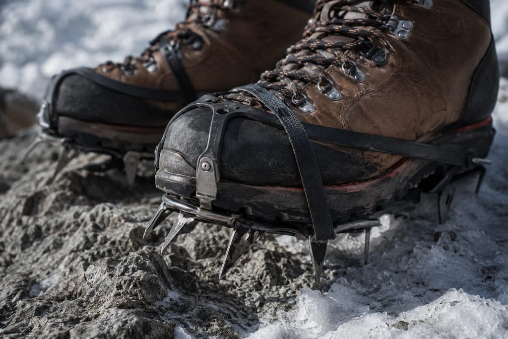 Gros plan sur des chaussures d'alpinisme équipées de crampons sur terrain rocheux