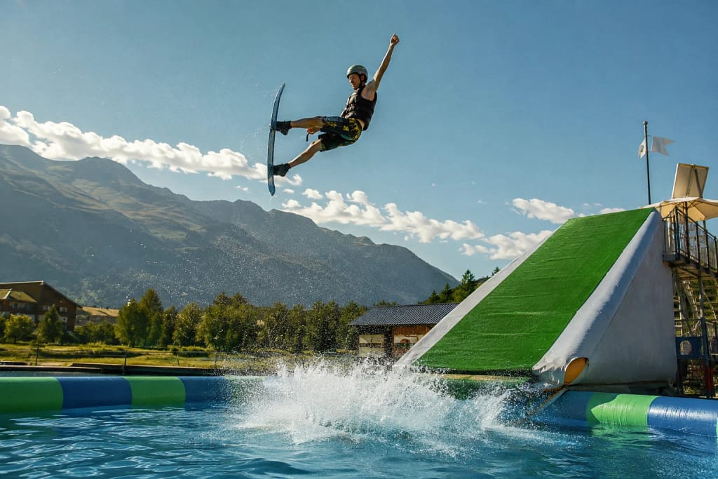 Saut spectaculaire sur un water jump avec éclaboussures dans un cadre montagnard