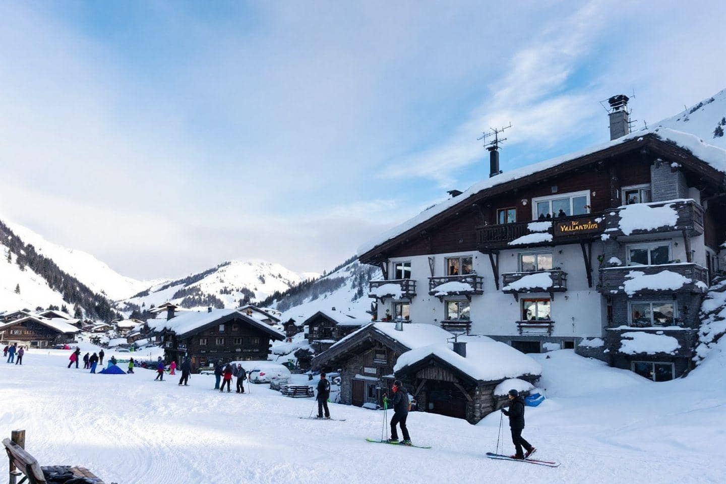 Village de montagne enneigé avec des skieurs sur les pistes.