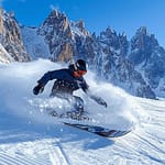 Snowboardeur descendant une pente abrupte avec un paysage montagneux enneigé en arrière-plan