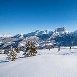 Séjour à la station de Villard-de-Lans : le plein d'évasion Piste de ski à Villard-de-Lans un jour ensoleillé. Skieurs descendent sur neige fraîche, avec montagnes enneigées et ciel bleu lumineux.