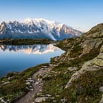 Deux randonneurs admirant le reflet du massif du Mont-Blanc dans les eaux calmes du Lac Blanc à Chamonix.